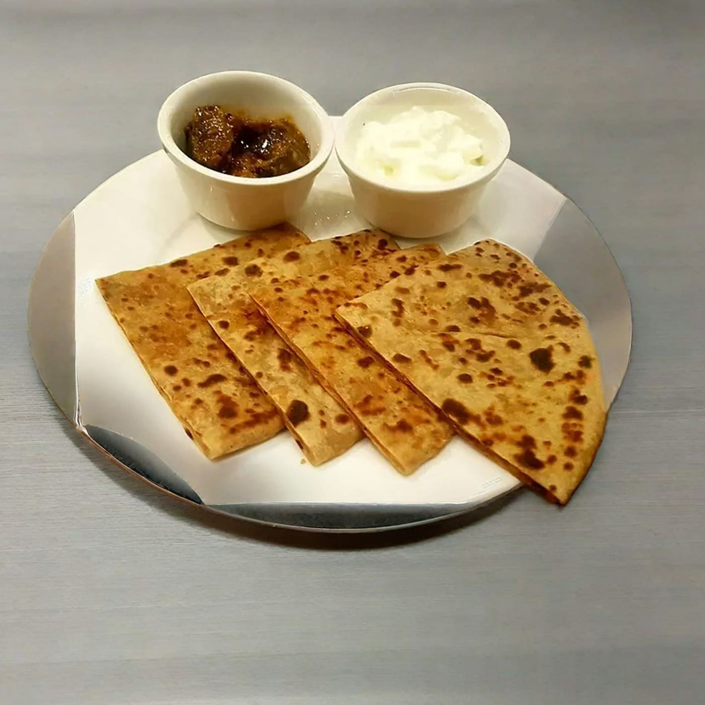 Paratha cut into wedges, served with curry and yoghurt